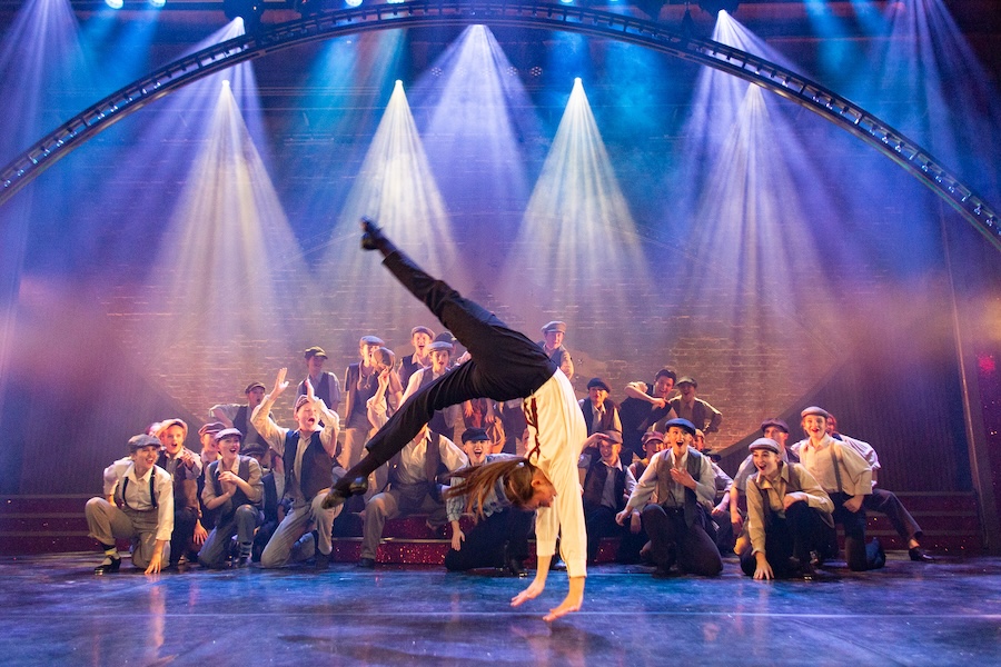 newsies number with girl flipping in forefront.